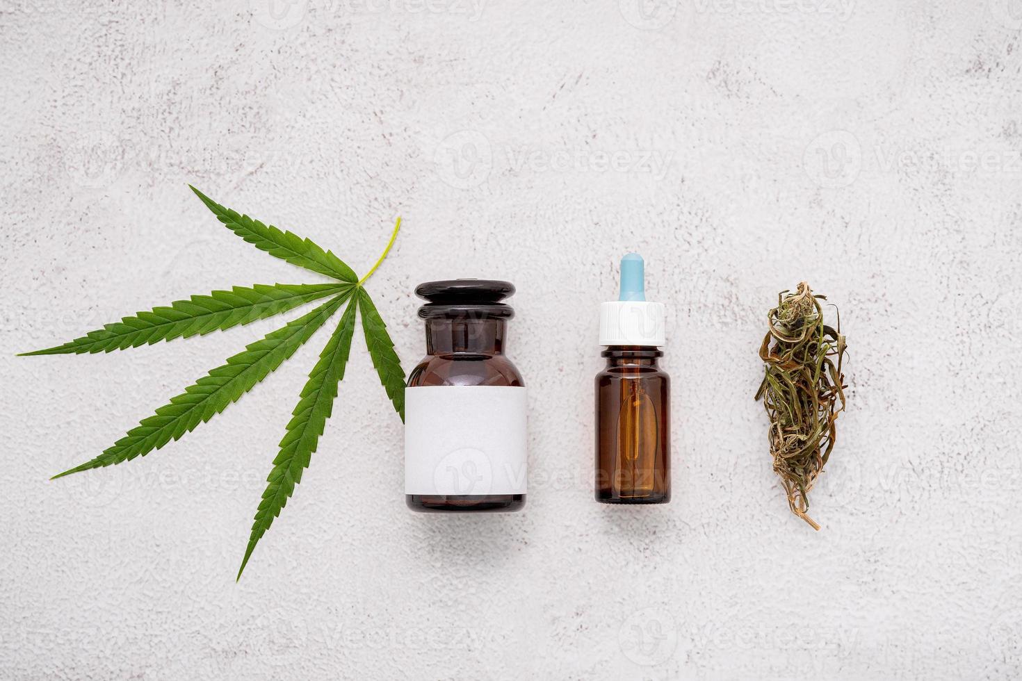 Glass bottle of cannabis oil with  hemp leaves set up  on concrete background. photo