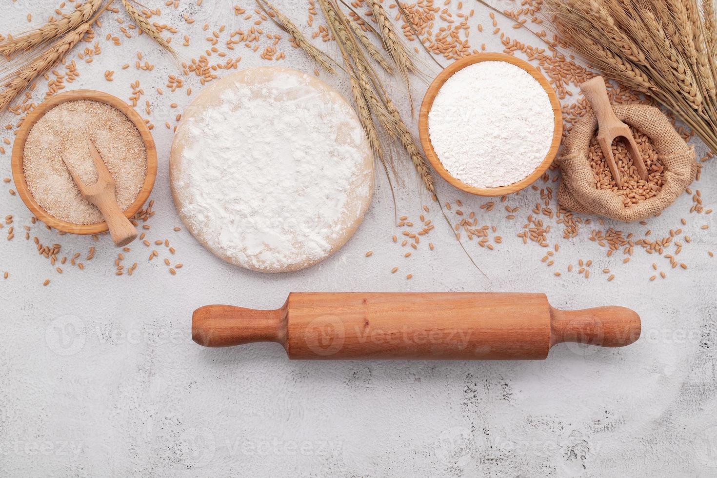 The ingredients for homemade pizza dough with wheat ears ,wheat flour and wheat grains set up on white concrete background. photo