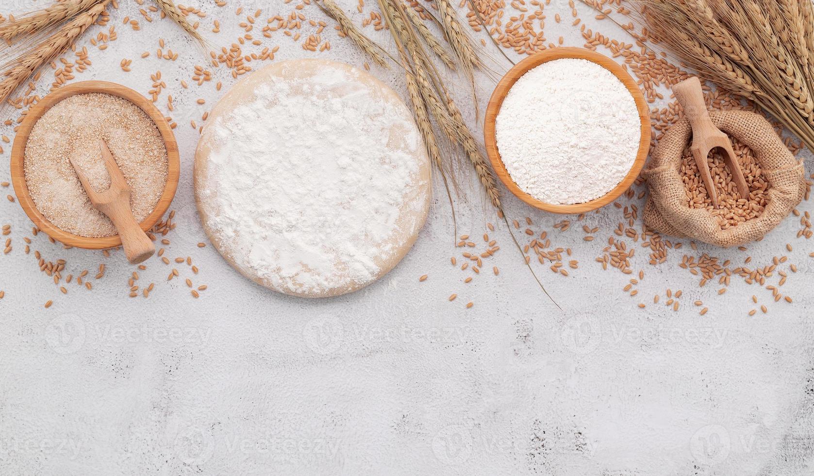 The ingredients for homemade pizza dough with wheat ears ,wheat flour and wheat grains set up on white concrete background. photo