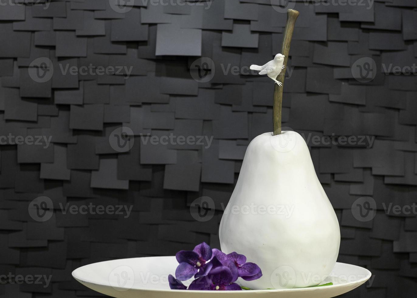 artificial ceramic pear on a plate with a bird photo