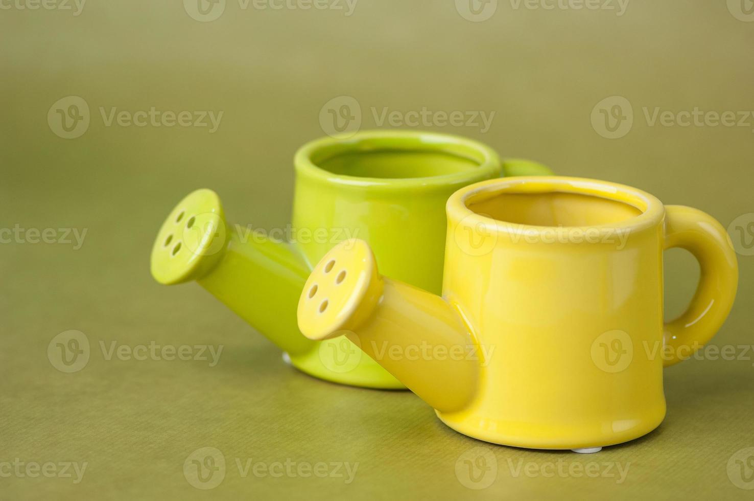 souvenir toy ceramic watering-can on a green background close up photo