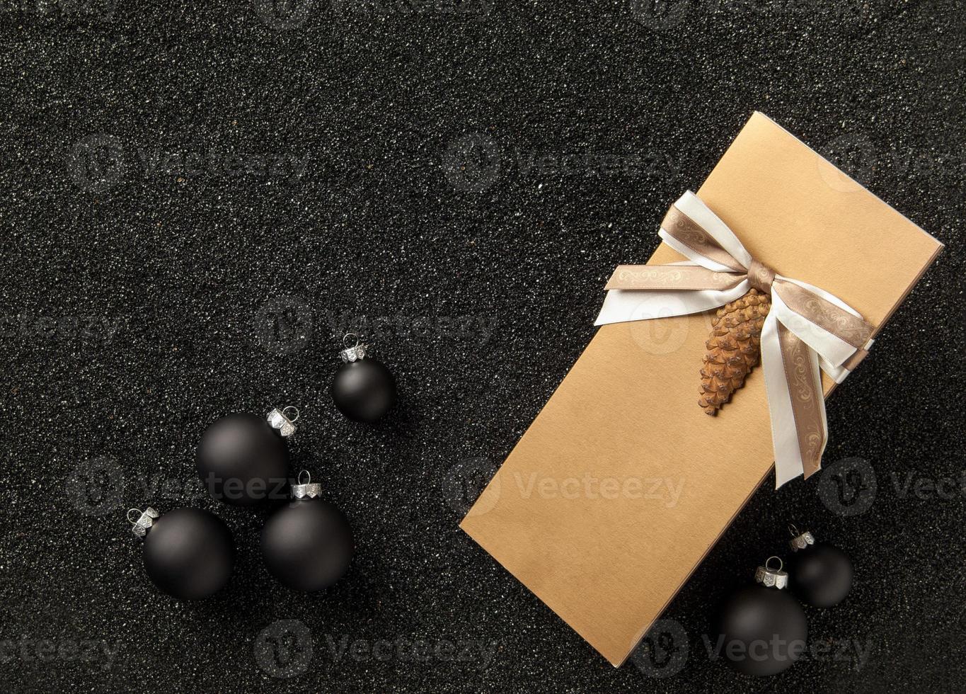 folleto de regalo con adornos para árboles de Navidad sobre un fondo negro granulado. volante con cinta sobre fondo negro granulado foto