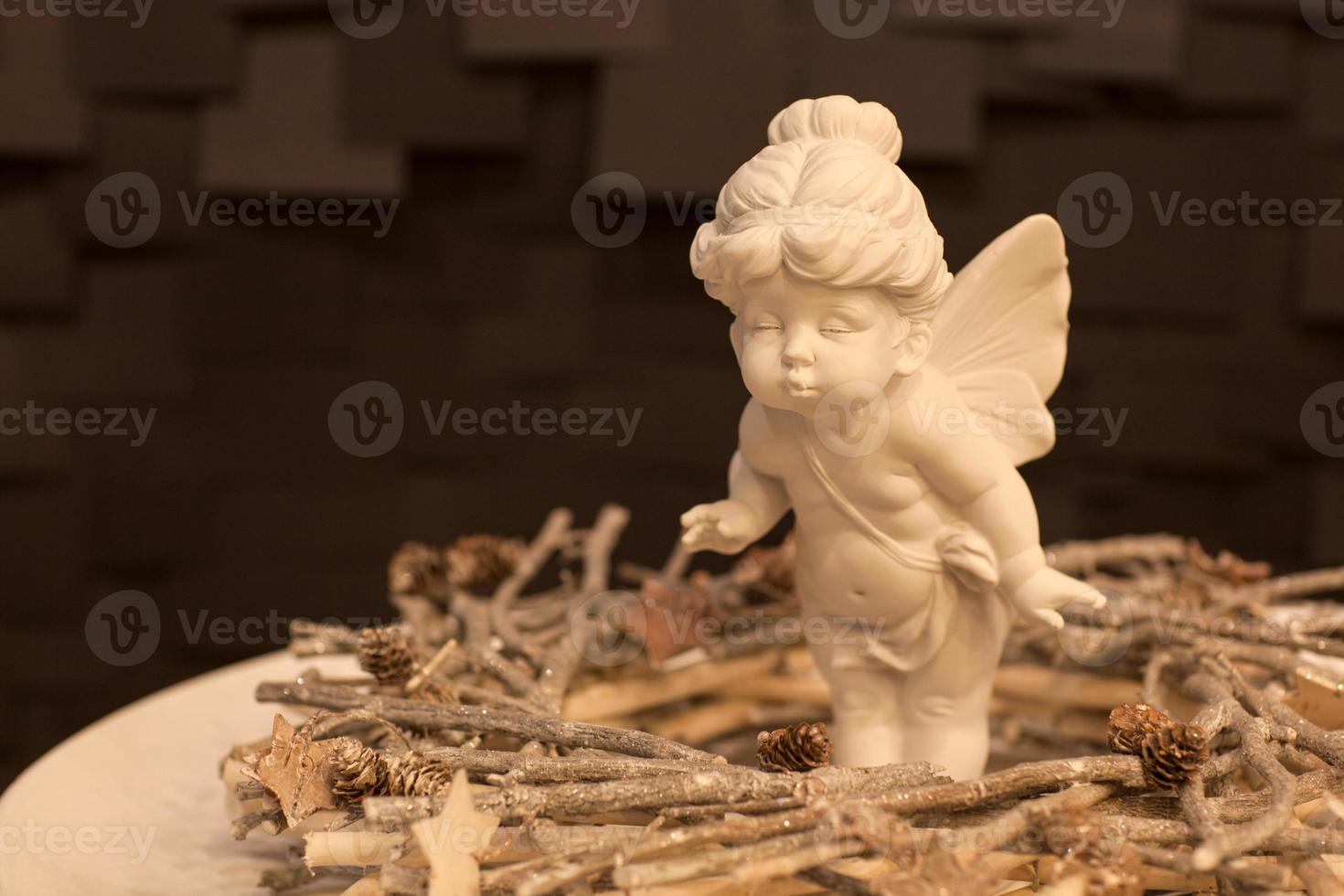 estatua de una niña ángel con alas en un plato blanco sobre un fondo oscuro foto