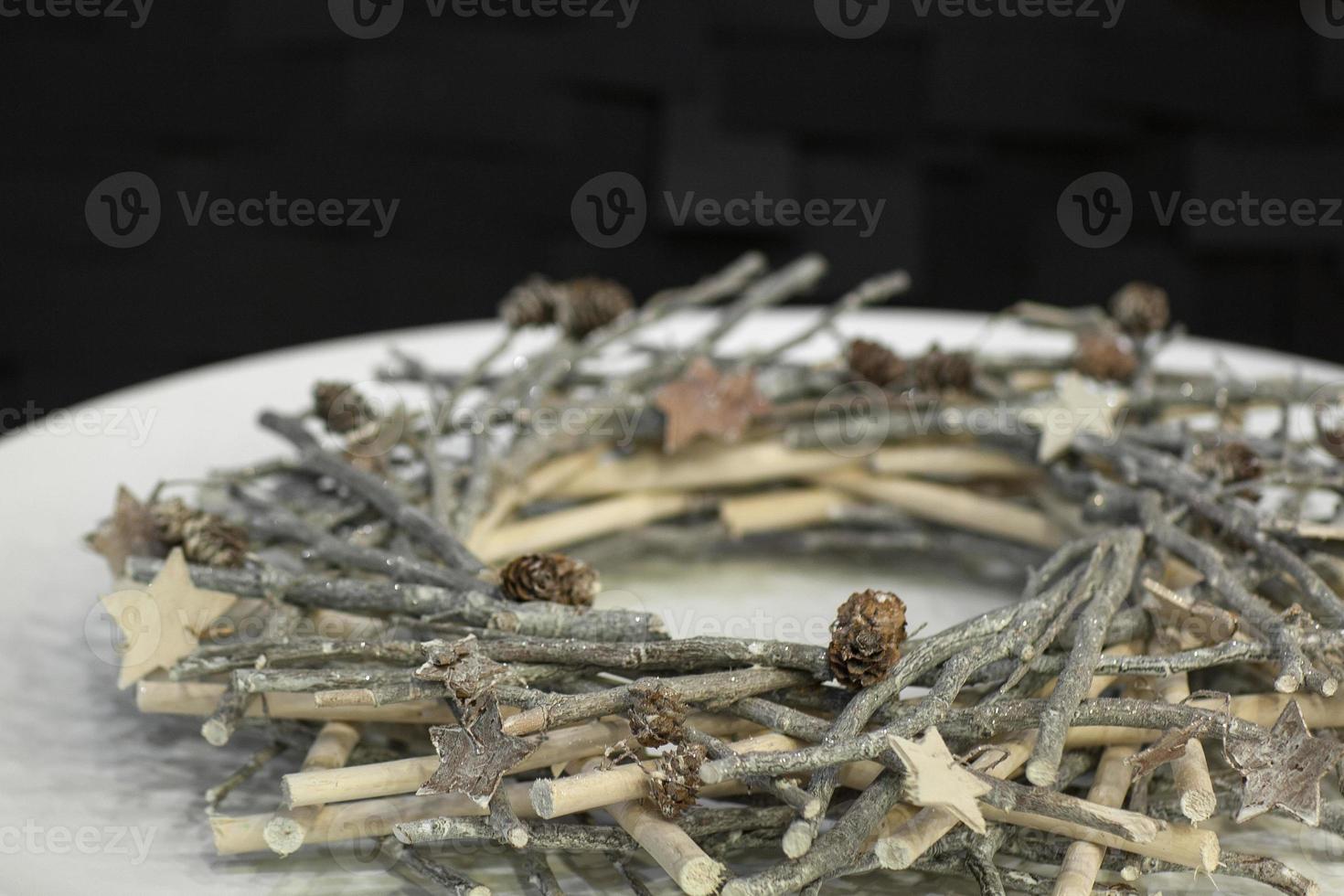 Christmas wreath of twigs decorated on a white plate on a dark background photo