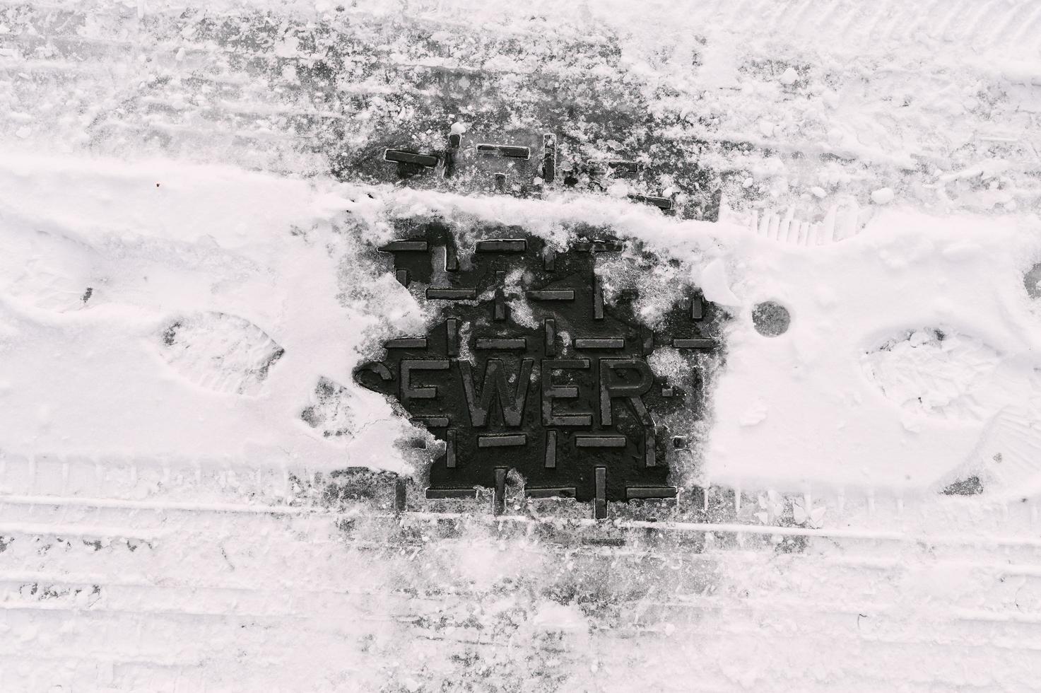 Sewer manhole cover covered by snow and ice photo