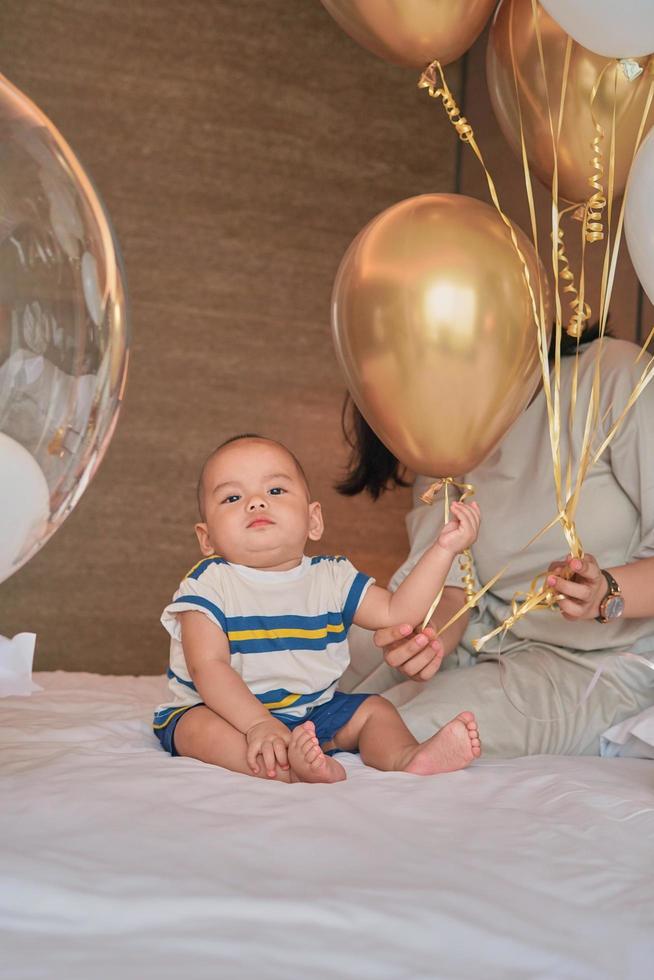 Portrait of happy little 6 month old Asian baby boy sitting on bed at home photo