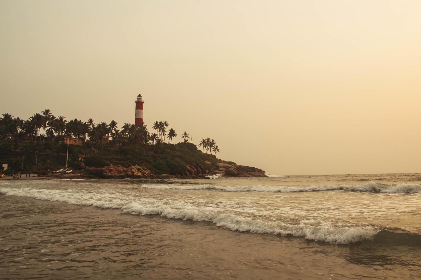 Lighthouse on the beach at morning dramatic sky in Kovalam, Kerala, India. Copy, empty space for text photo