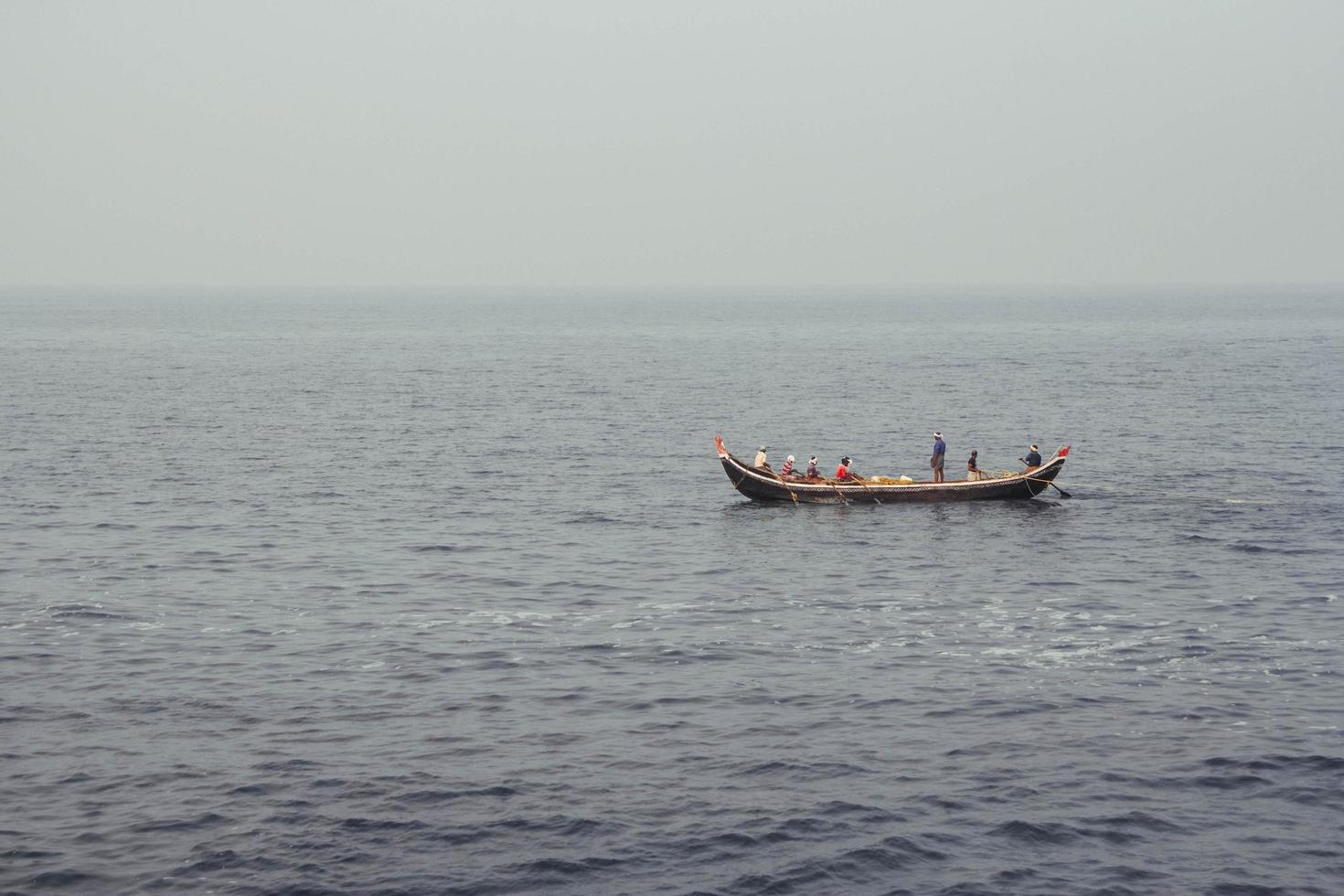 Asian fishermen in a wooden boat sail in the middle of the sea. Copy, empty space for text photo