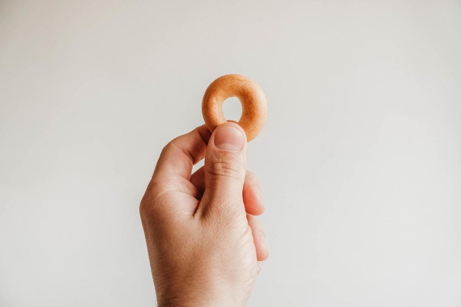 Small bagel drying in hand on white background. Copy, empty space for text photo