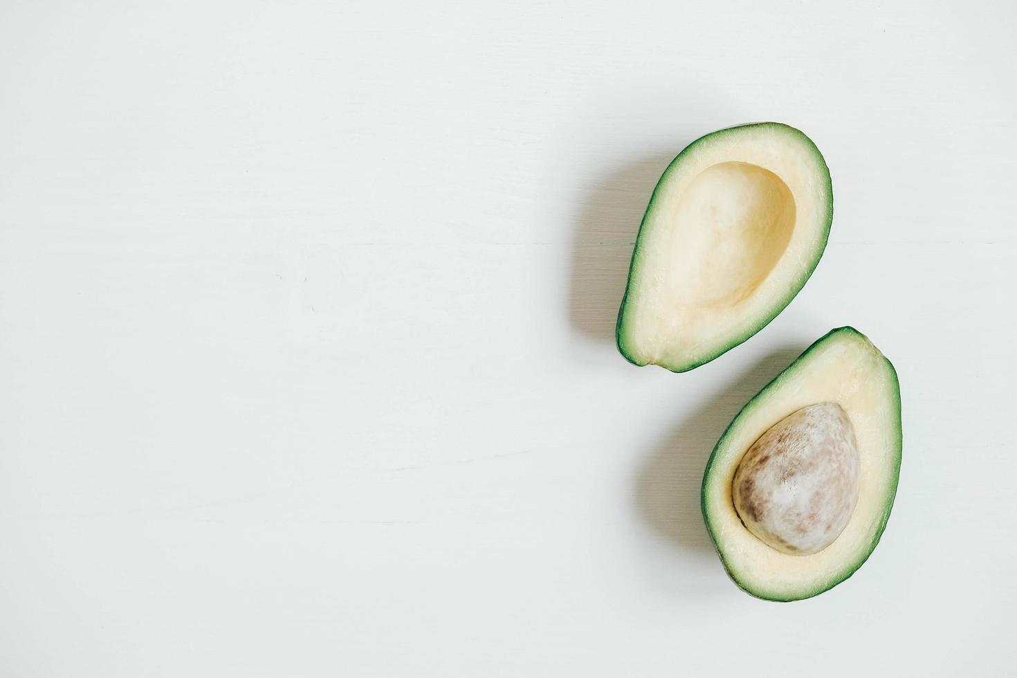 Sliced avocado on a white wooden background. Top view. Copy, empty space for text photo