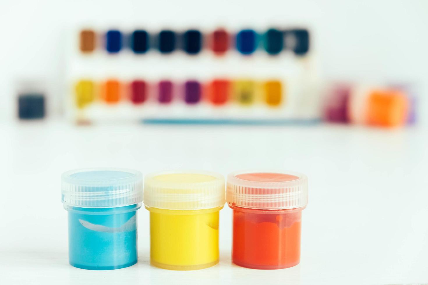 Colorful gouache paints and brush for painting on white wooden table. Copy, empty space for text photo