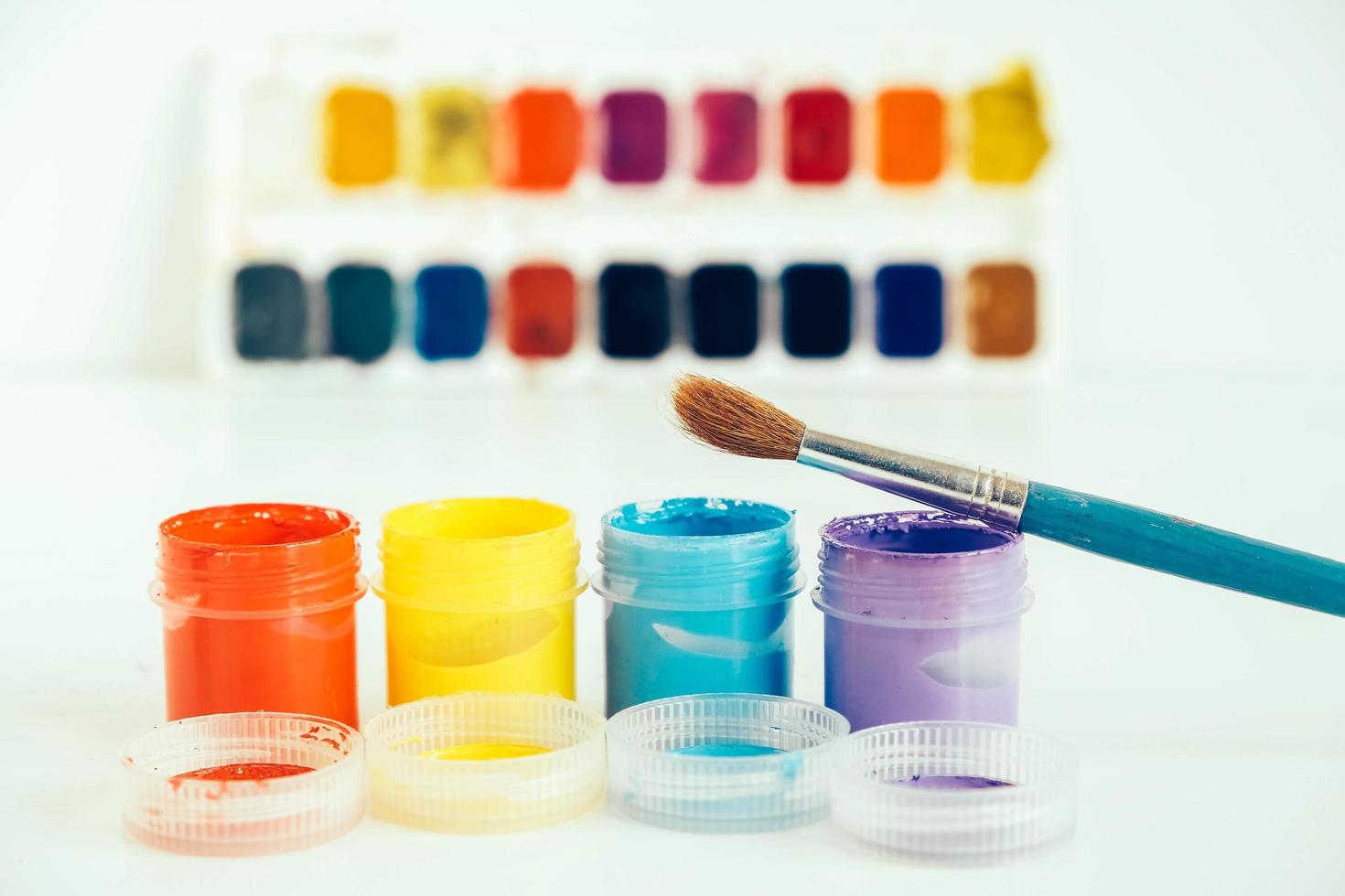 Colorful gouache paints and brush for painting on white wooden table photo