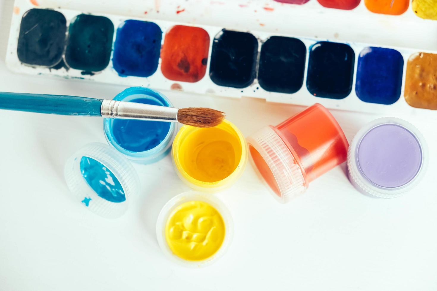 Colorful gouache paints and brush for painting on white wooden table photo