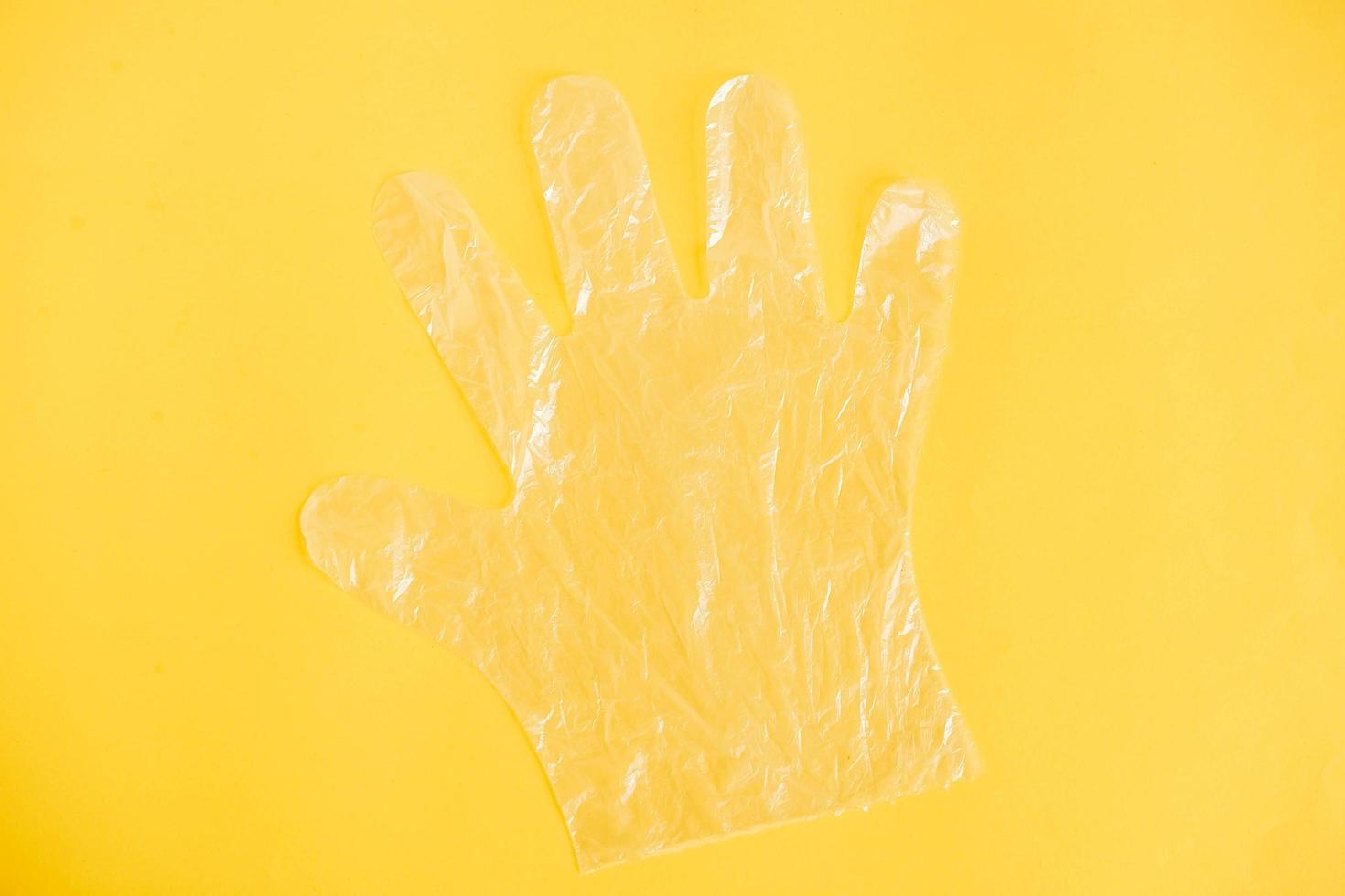 Disposable transparent plastic glove on a yellow background photo