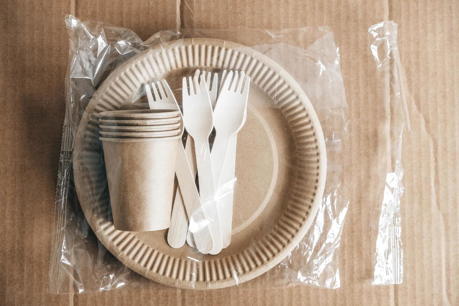 Wooden forks and paper cups with plates on kraft paper background photo