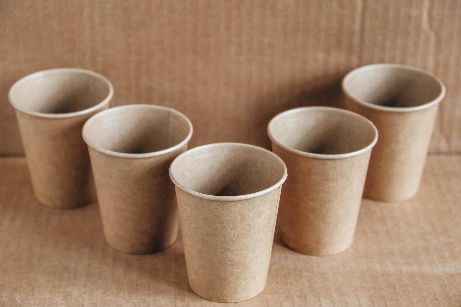 Disposable paper cups on kraft paper background. Eco friendly disposable tableware. Zero waste concept. Copy, empty space for text photo