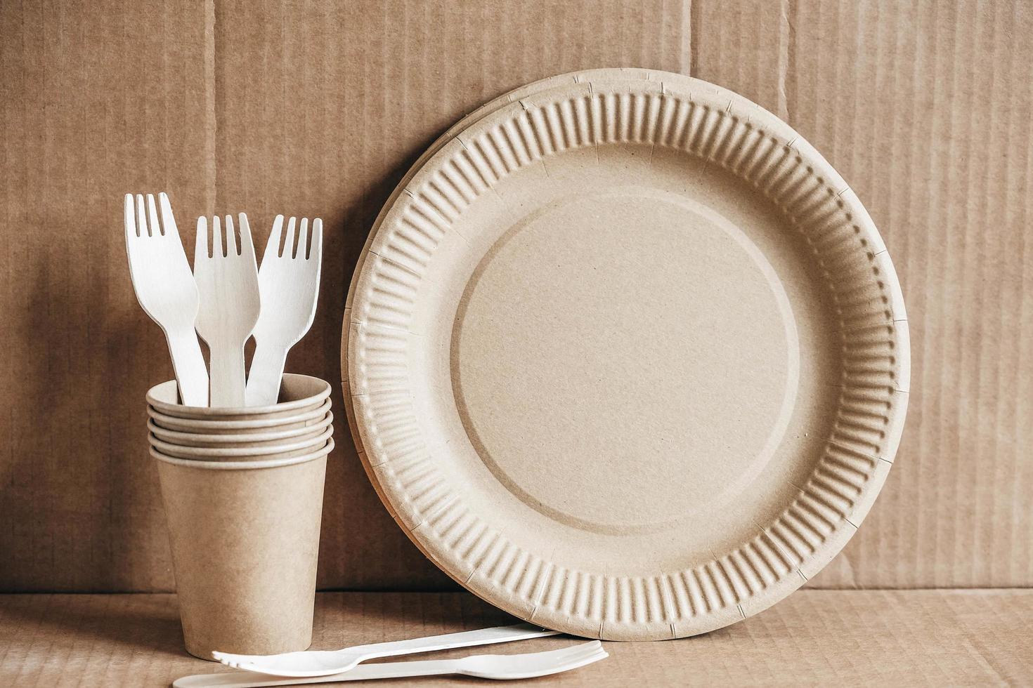 Wooden forks and paper cups with plates on kraft paper background photo