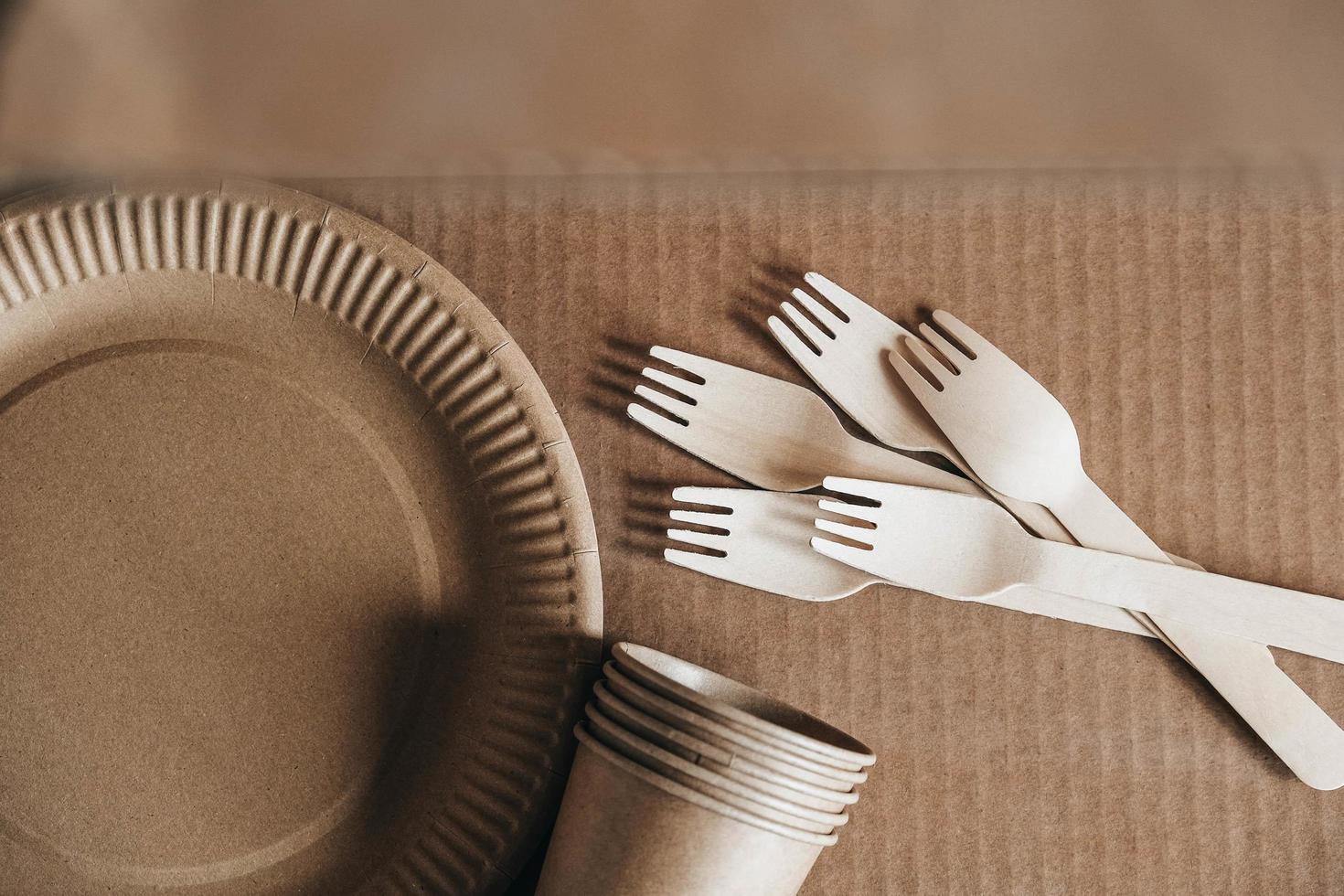 Wooden forks and paper cups with plates on kraft paper background photo