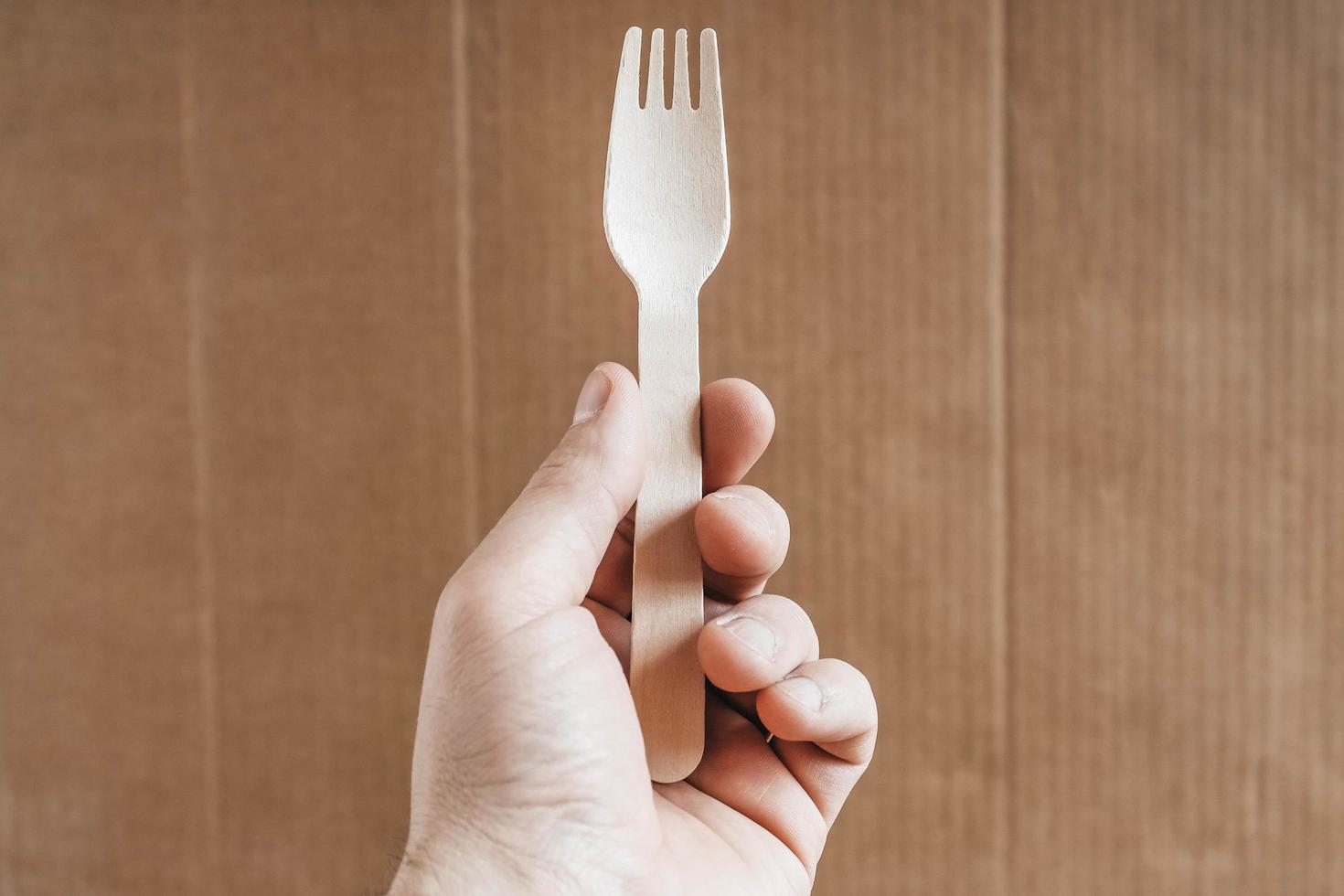 Men hand holding wooden fork on cardboard background photo