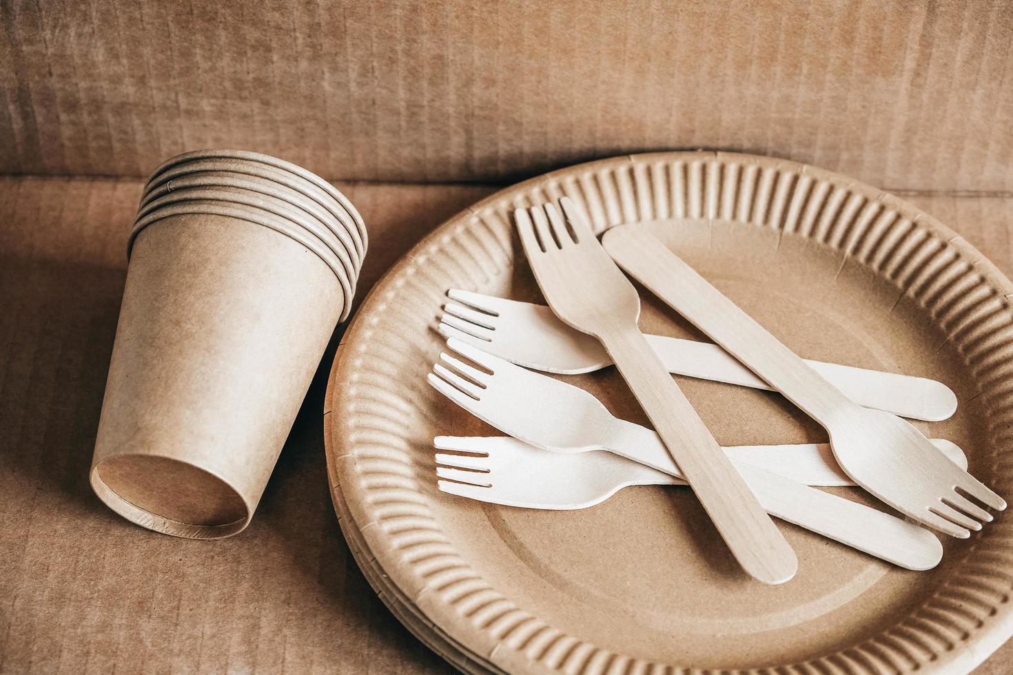 Wooden forks and paper cups with plates on kraft paper background photo