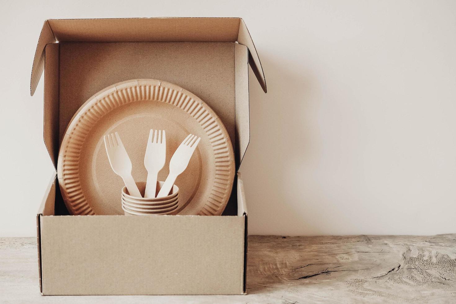 Wooden forks and paper cups with plates on box paper background photo