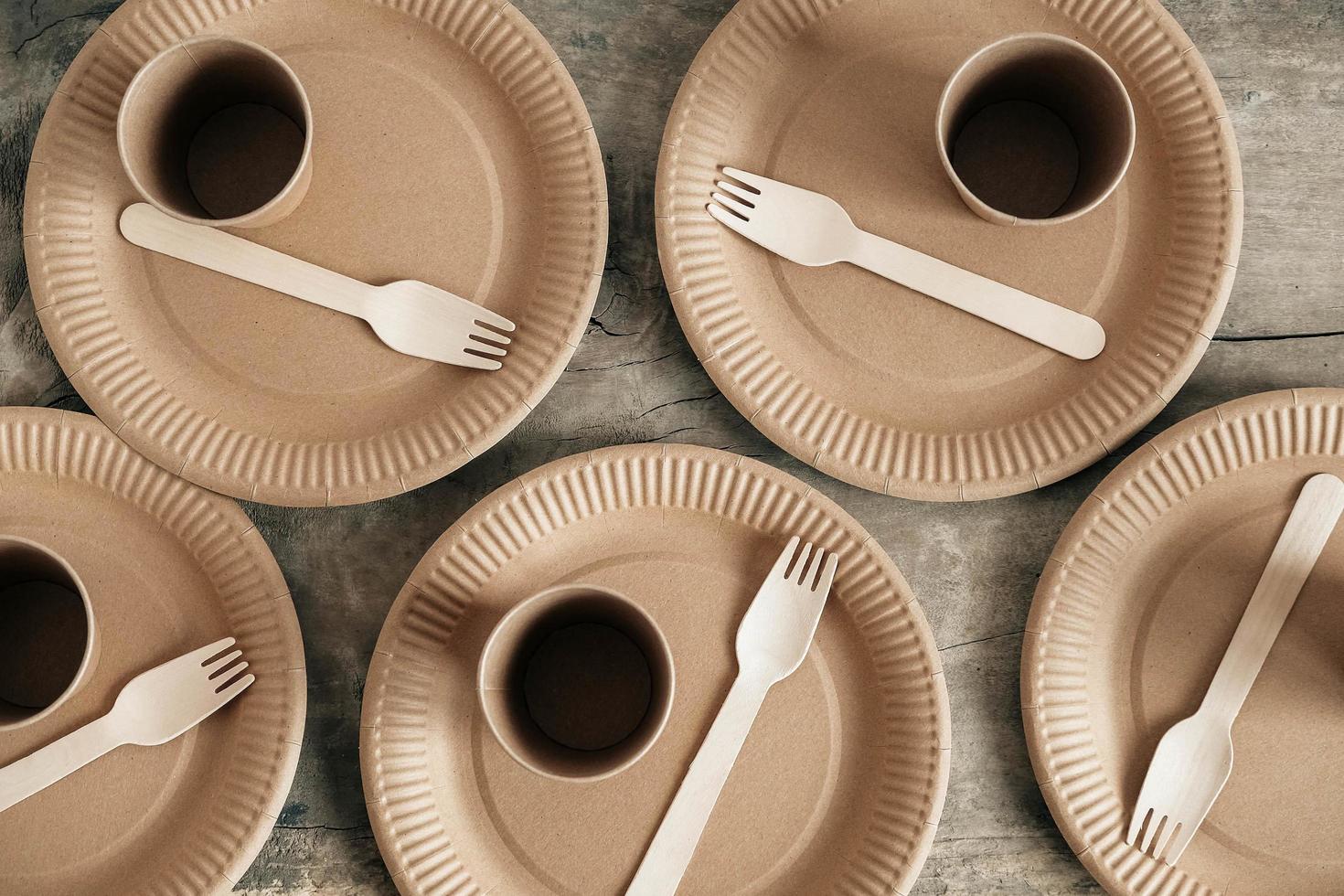 Wooden forks and paper cups with plates on wooden background photo