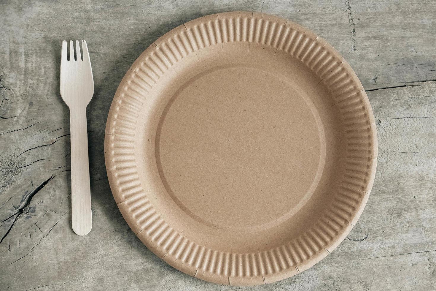 Wooden fork and paper plate on wooden background photo