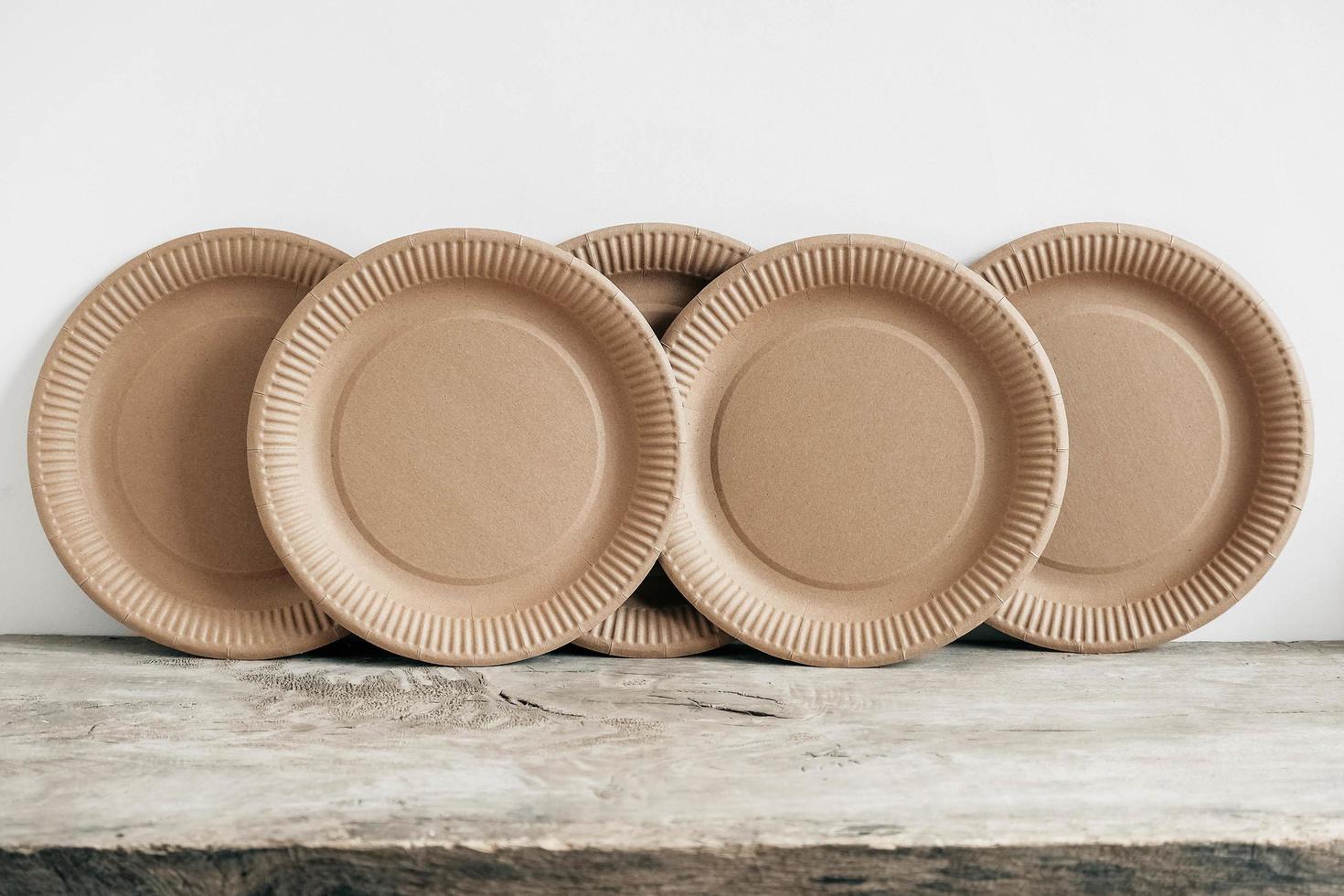 Disposable kraft paper plates on wooden background photo