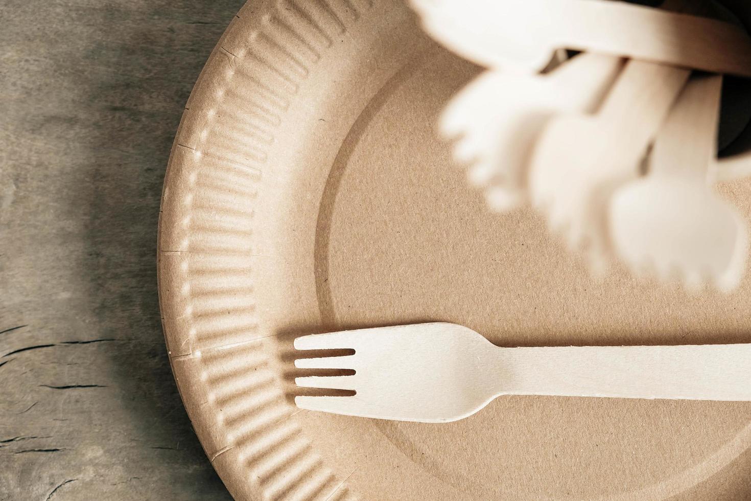 Wooden forks and paper cups with plates on wooden background photo