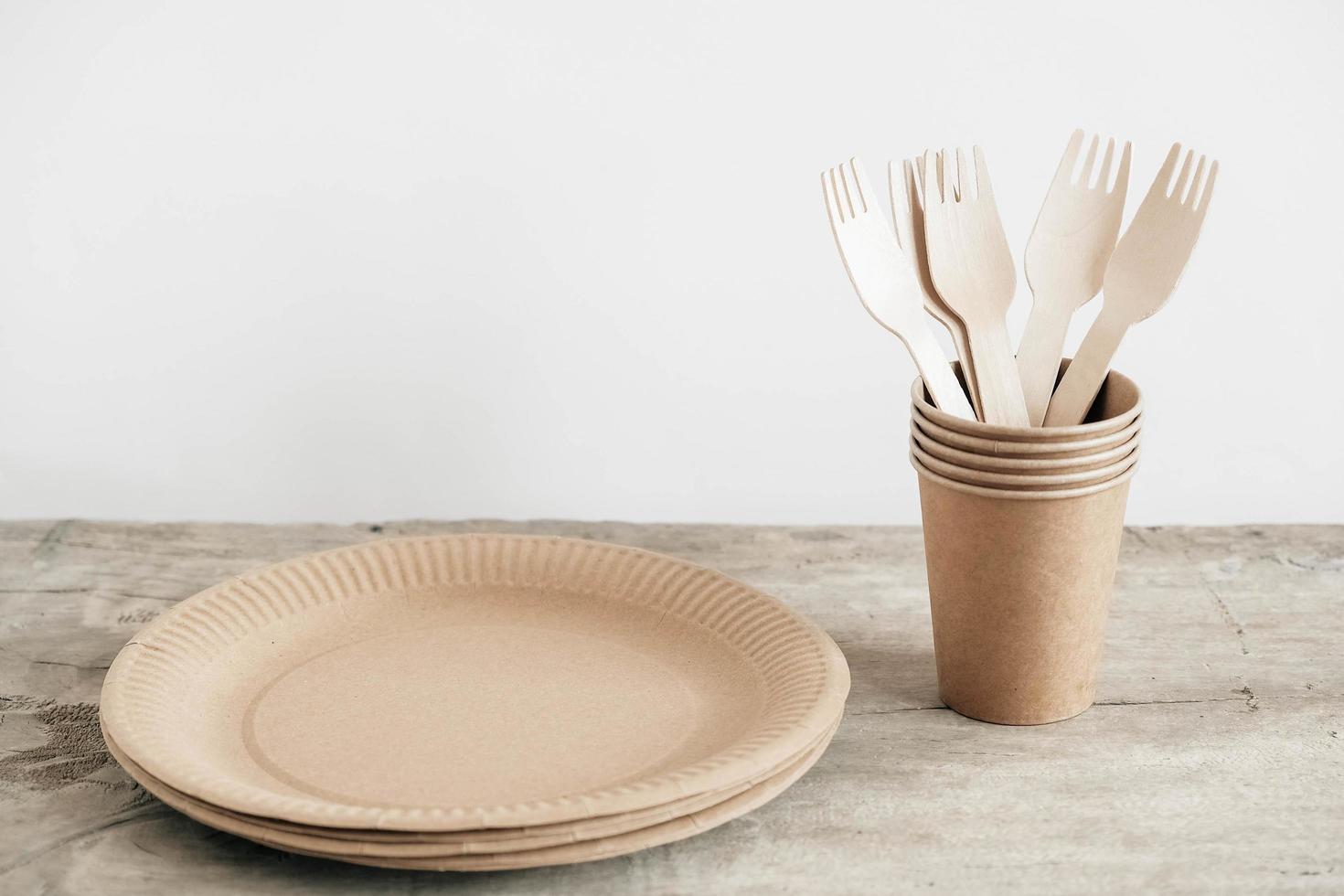 Wooden forks and paper cups with plates on wooden background photo