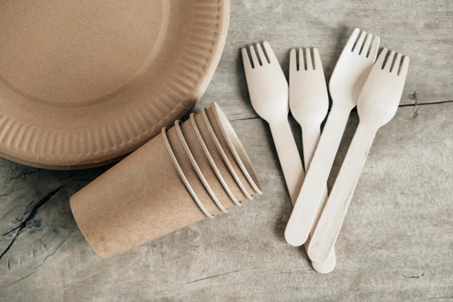 Wooden forks and paper cups with plates on wooden background photo