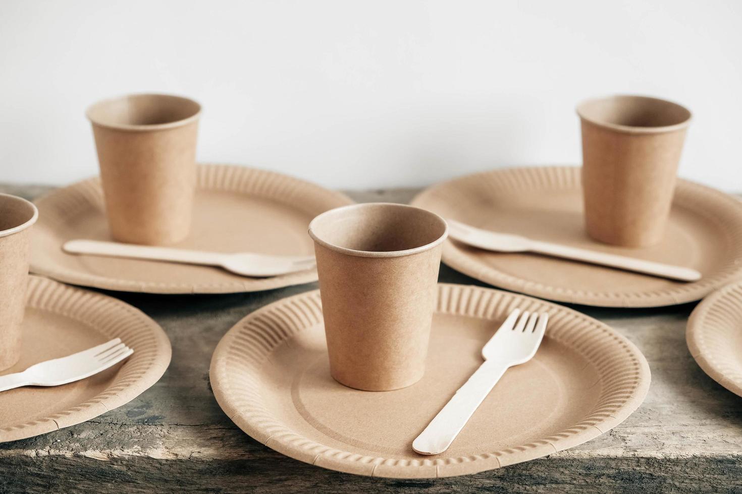 Wooden forks and paper cups with plates on wooden background photo
