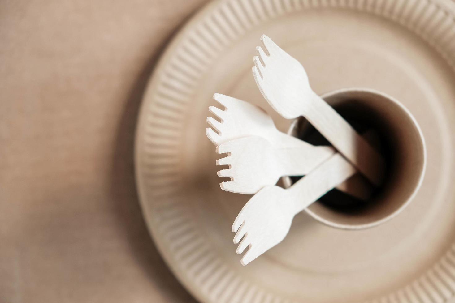 Wooden forks and paper cups with plates on kraft paper background photo