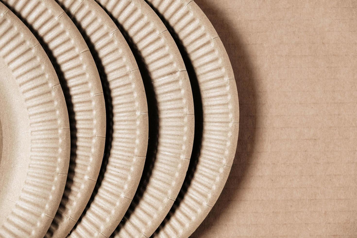 Disposable paper plates on kraft paper background. Eco friendly disposable tableware photo