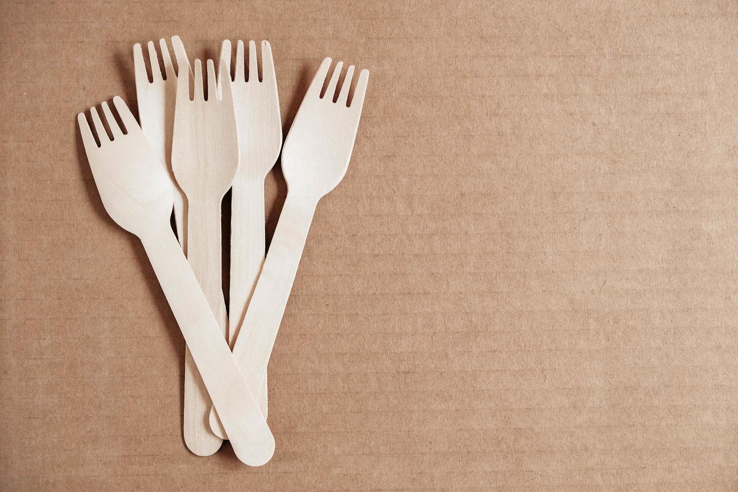 Wooden forks on a cardboard background. Eco friendly disposable tableware. Top view. Copy, empty space for text photo