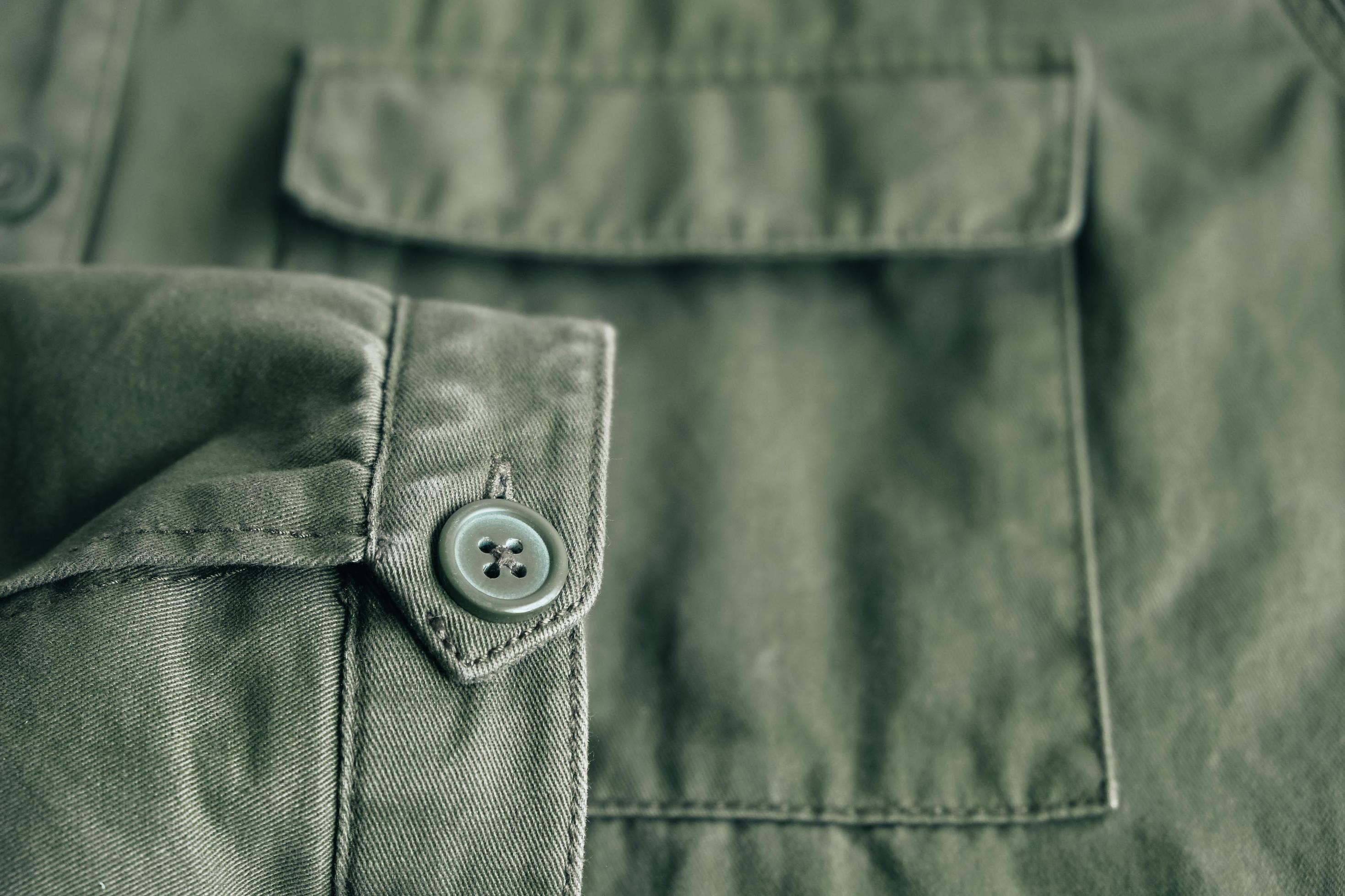Background of folding sleeve of green jacket on pocket and buttonhole