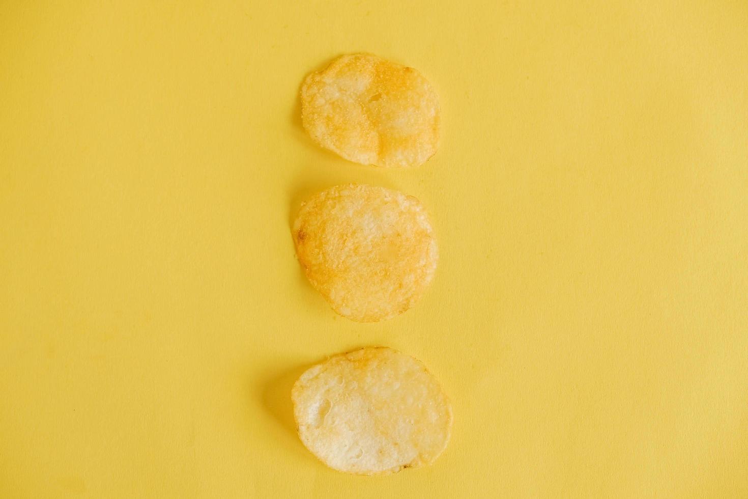 Three potato chips on a yellow background photo