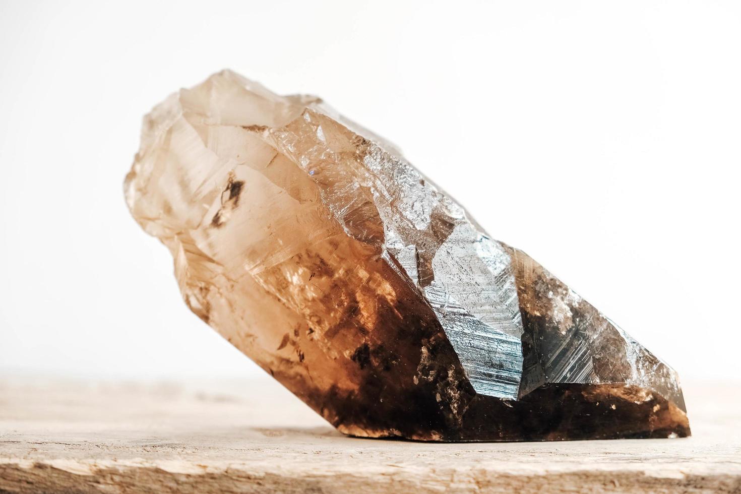 Smoky quartz crystal on a wooden surface on a white background. Copy, empty space for text photo