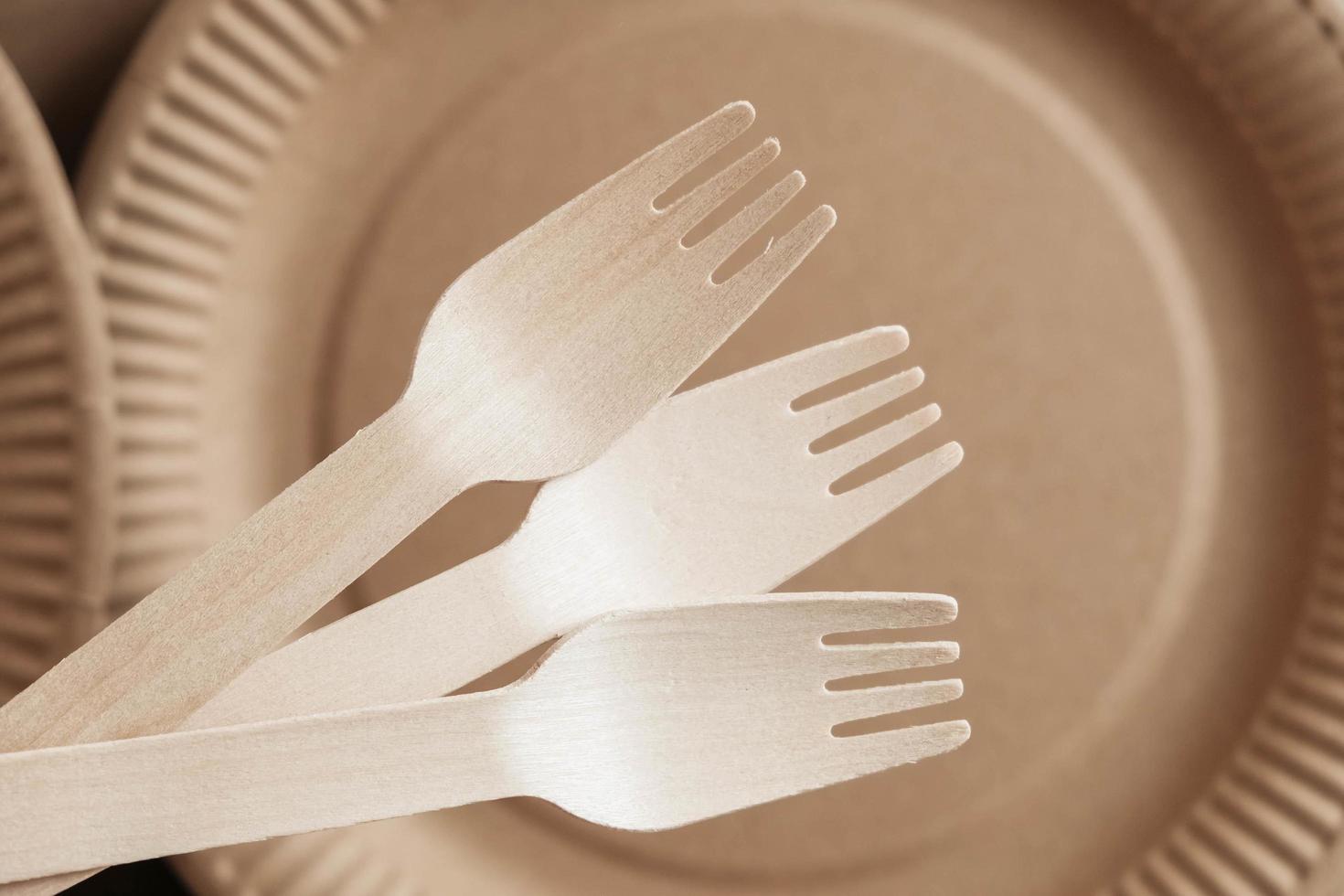 Wooden forks and plates on kraft paper background photo