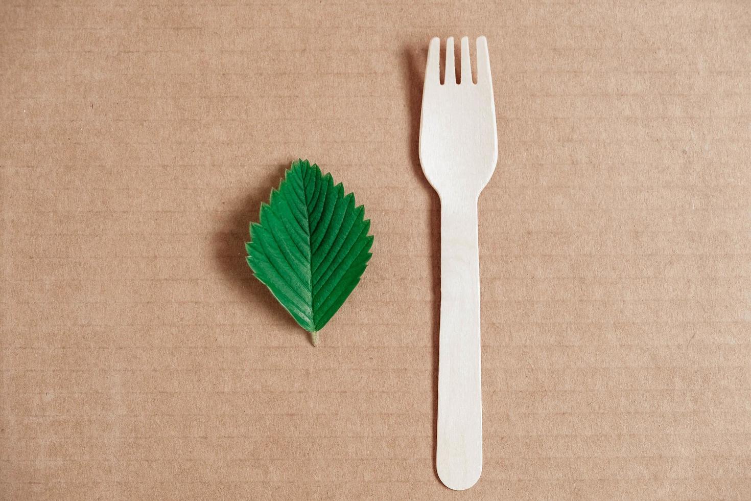 Wooden fork on a cardboard background. Eco friendly disposable tableware. Top view. Copy, empty space for text photo