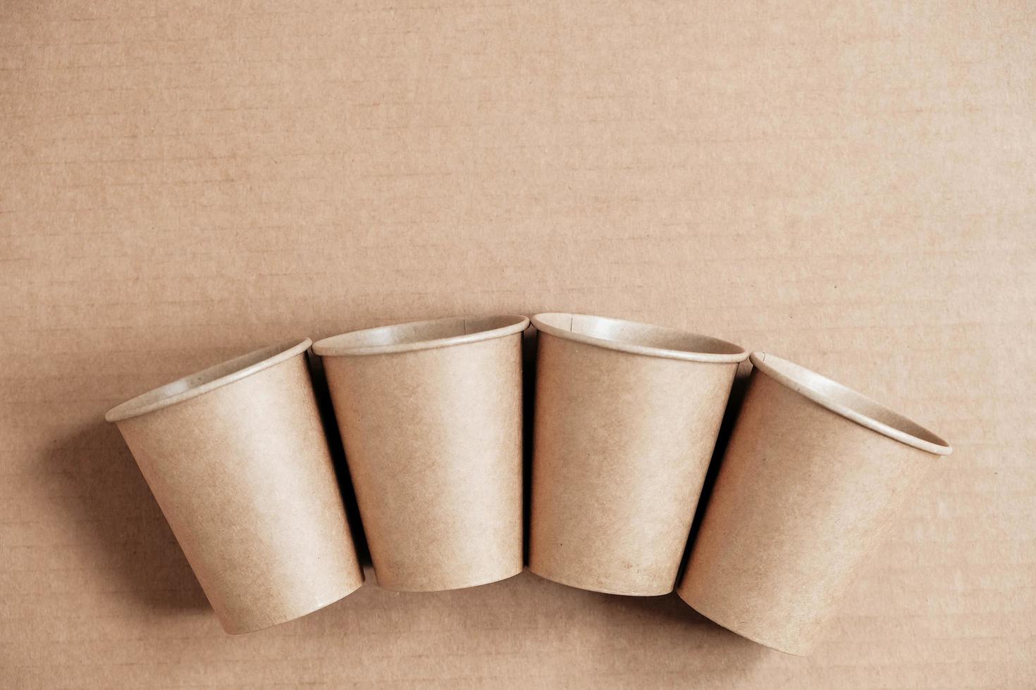 Disposable paper cups on kraft paper background. Eco friendly disposable tableware. Zero waste concept. Top view. Copy, empty space for text photo