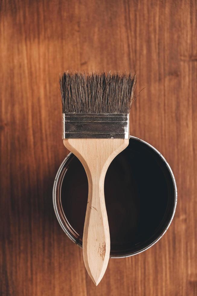 Paint brush on a jar with brown paint on a wooden background photo