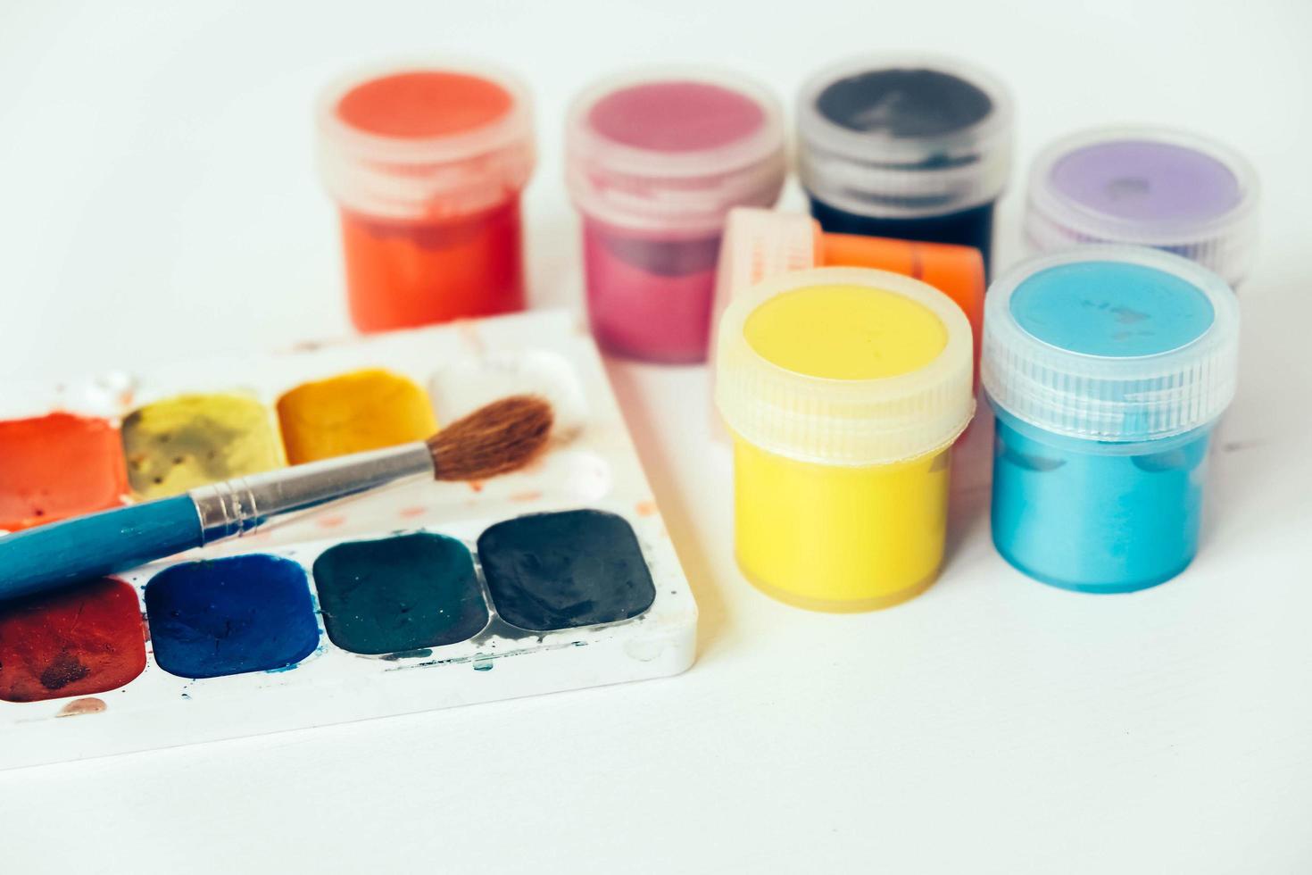 Colorful gouache paints and brush for painting on white wooden table photo