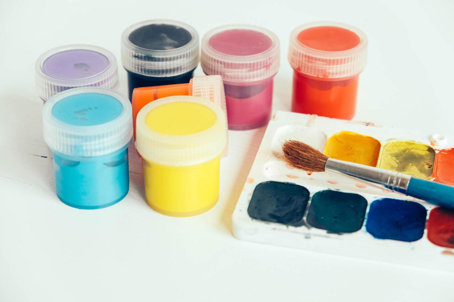Colorful gouache paints and brush for painting on white wooden table. Copy, empty space for text photo
