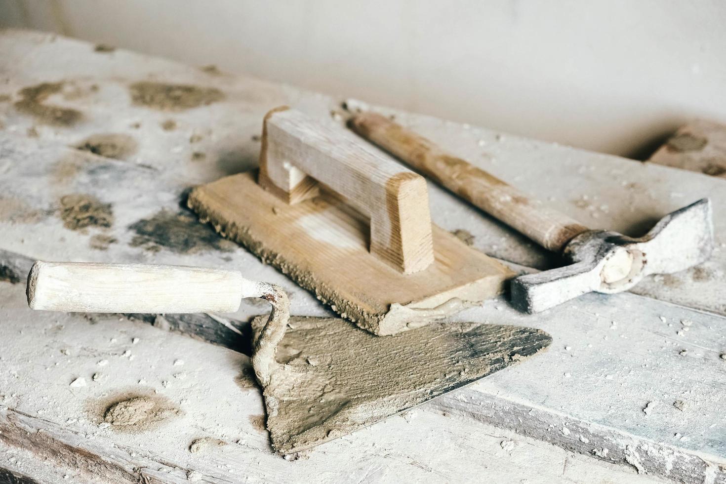 Old construction tools for plaster on vintage wood bench. Trowels and other masonry tools. Copy, empty space for text photo