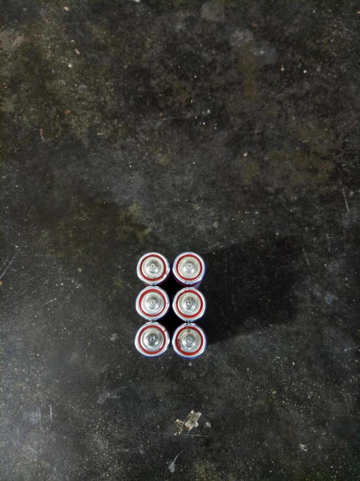 batteries lined up against a cement floor background photo