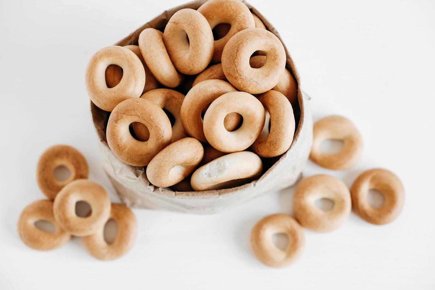 Drying or round bagels in a paper bag on a white wooden background. Top view. Copy, empty space for text photo