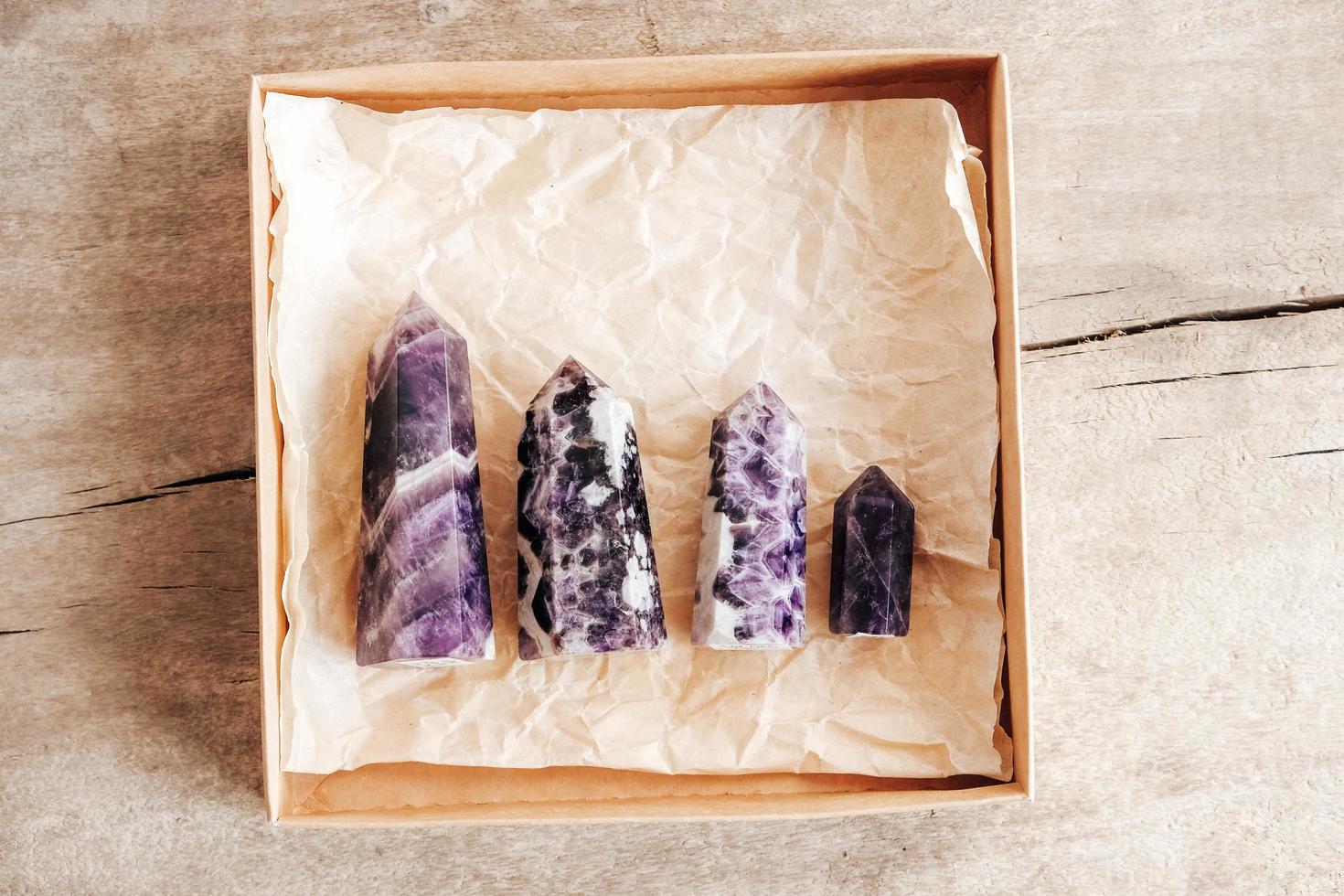 Amethyst polished crystal point in a kraft paper box on wooden background photo