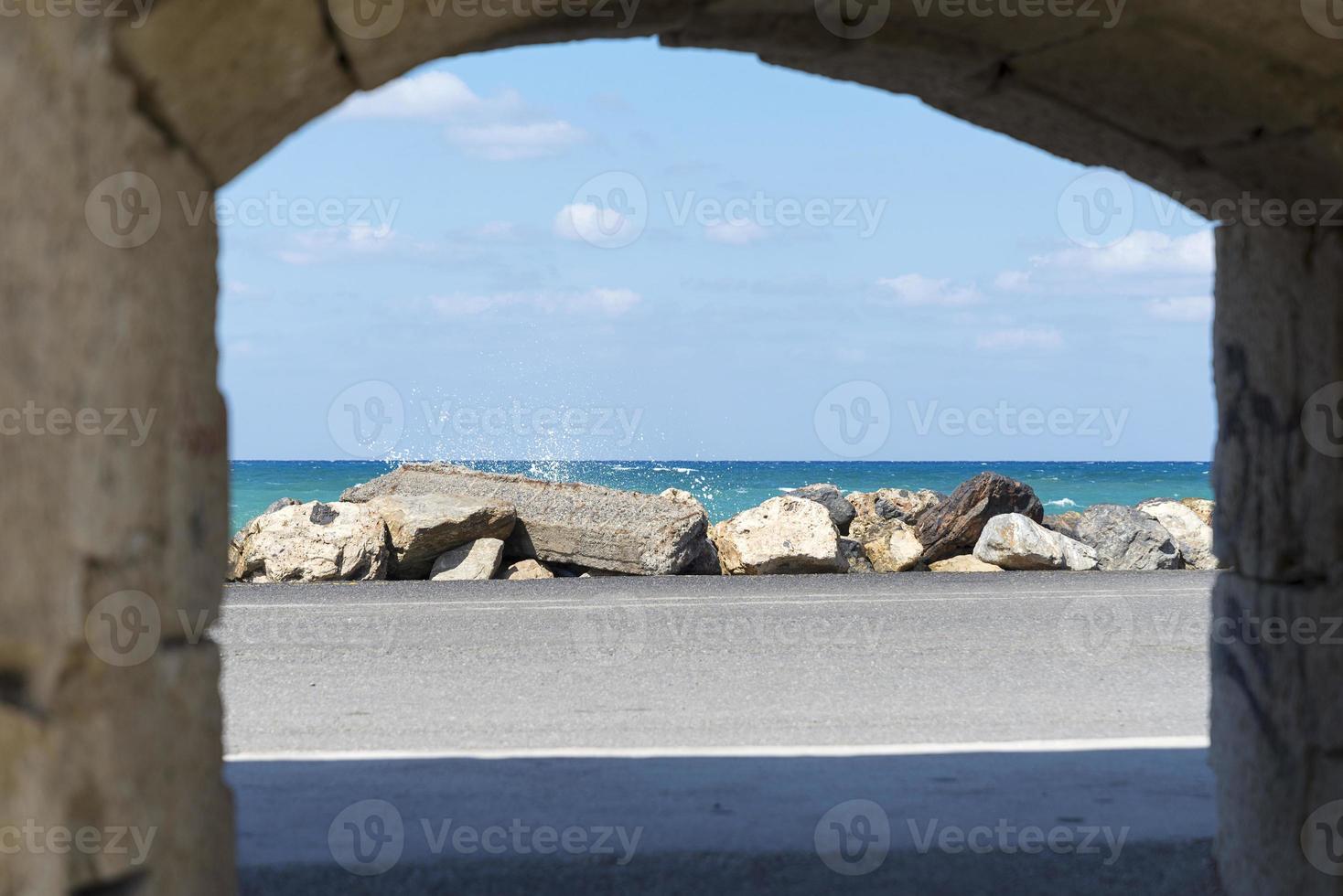 The waves breaking on a stony beach, forming a spray. Wave and splashes on beach. Waves crashing onto rocks. photo