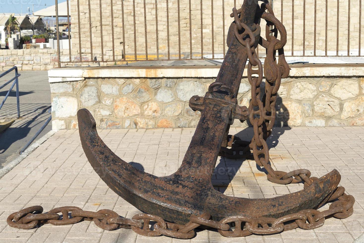 Old anchor lies on stones. Sunny day photo